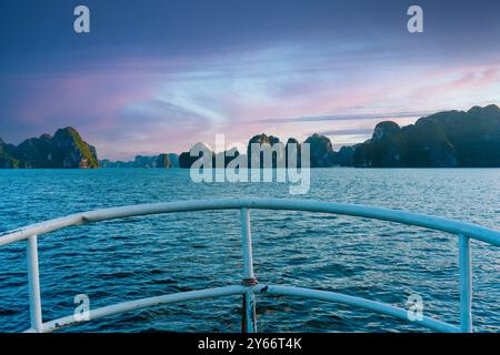 original view of Ha Long Bay in Vietnam taken from the bow of a boat sailing in the archipelago, a landmark tourist spot at sunset Stock Photo