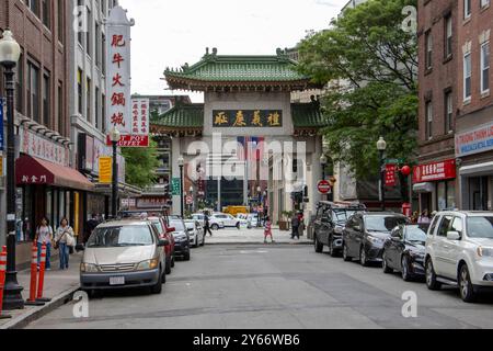 The image shows a bustling street scene in a Chinatown district, dominated by a large traditional Chinese gateway or 'paifang' with green tiled roofs Stock Photo