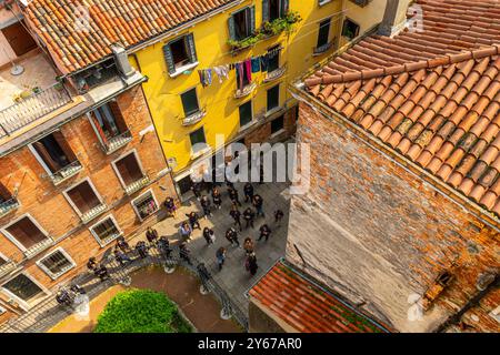 Looking down from Scala del Bovolo , a multi-arch spiral staircase at people in the the small square below in the San Marco sestiere of Venice,Italy Stock Photo