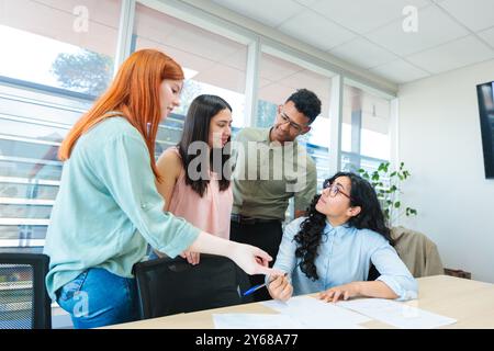 Multiracial teamwork collaborating on business strategies, around a table with documents in co-working office Stock Photo