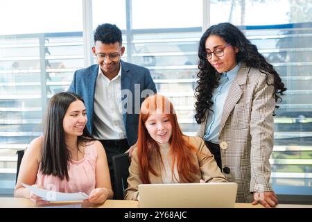 Group of Young Cheerful Business People Collaborating on a New Project While Sitting in Well-lit Conference Room Stock Photo