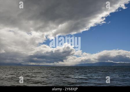 A sky full of beautiful clouds, lit by the sun. Before that it was raining. The rippling waters of the lake overflow in the light. Stock Photo
