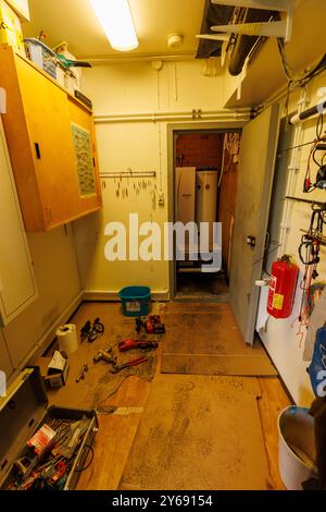 Tools and work site indoors, replacing old oil boiler with air to water heatpump . Boiler room door open and heatpump at the background, Finland Stock Photo