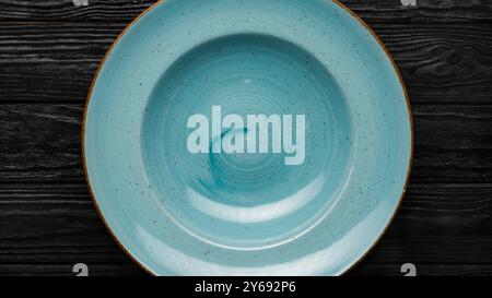 Empty blue plate on black wooden table, top view, food concept Stock Photo