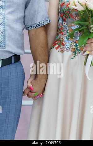 Elegant Couple Holding Hands in Romantic Embrace with Colorful Nail Art. Stock Photo