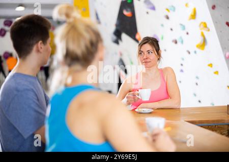 Woman chatting with friends at bar counter in climbing club during coffee break Stock Photo