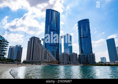 Al Reem Island in Abu Dhabi features sleek, modern high-rises, unique architecture, reflective waterfront Stock Photo