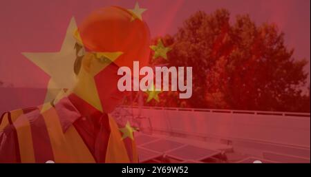 Construction worker in safety gear over Chinese flag image with solar panels background Stock Photo