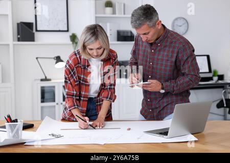 Architects making engineering drawing at wooden table in office Stock Photo