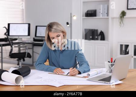 Architect making engineering drawing at table in office Stock Photo