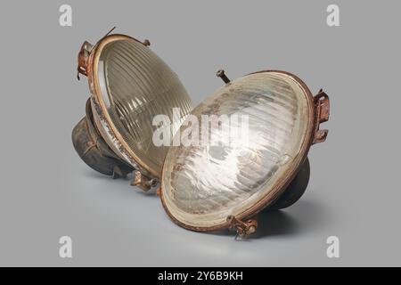 old discarded car headlights isolated gray background, spare parts in scrapyard close-up view, damaged outdated or no longer functional vehicle parts Stock Photo