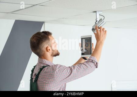 Male worker with tablet computer installing alarm system in room Stock Photo