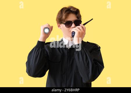 Male security guard with flashlight and two-way radio on yellow background Stock Photo