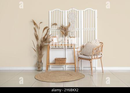 Armchair, table and pampas grass in vase near beige wall Stock Photo