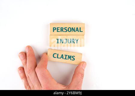 Words PERSONAL INJURY CLAIMS assembled from wooden blocks with the help of a hand, a view from above Stock Photo