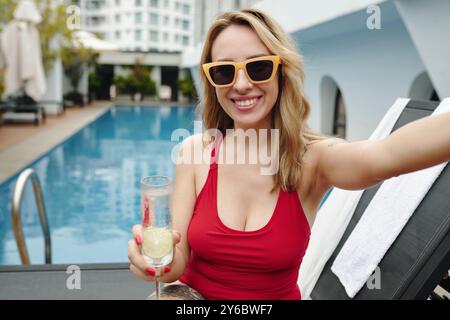 Smiling Woman Holding Drink by Poolside Stock Photo