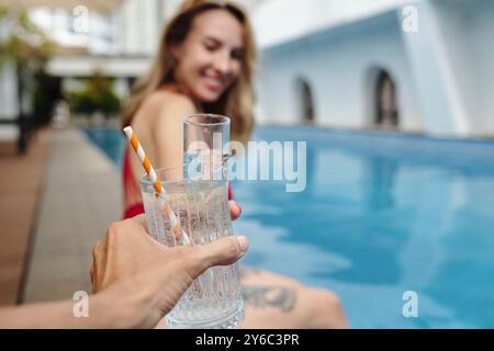 Holding Glass of Water by Poolside with Woman Smiling Stock Photo