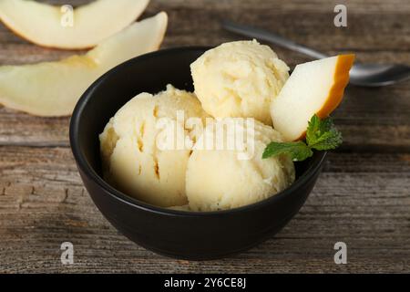 Scoops of melon sorbet with mint and fresh fruit in bowl on wooden table, closeup Stock Photo