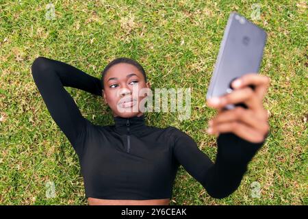 woman lying on the grass taking selfie on mobile Stock Photo