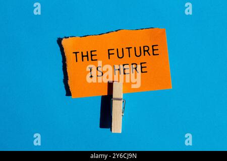 The future is here message written on ripped torn orange paper on blue background. Conceptual the future is here symbol. Copy space. Stock Photo