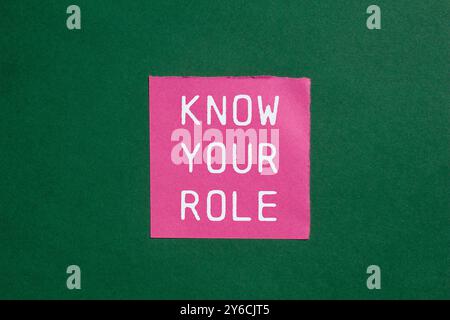 Know your role message written on ripped torn pink paper on green background. Conceptual know your role symbol. Copy space. Stock Photo