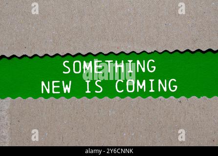 Something new is coming message written on ripped torn paper on green background. Conceptual something new is coming symbol. Copy space. Stock Photo