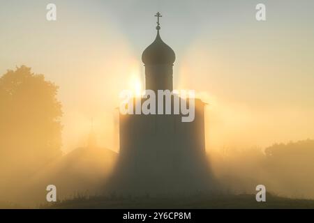 Silhouette of the medieval Church of the Intercession on the Nerl against the background of the rising sun in the morning fog. Bogolyubovo, Golden Rin Stock Photo