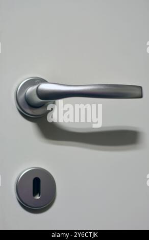 a metal handle and metal hole for a key on white wooden door Stock Photo