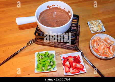 Chocolate fondue with fruits on wooden table. Cooking fondue Stock Photo