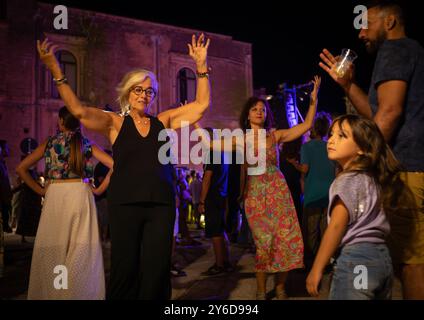 People enjoy Pizzica dance at a concert by Canzoniere Grecanico Salentino, or CGS, in Alessano, Lecce Province, Apulia, Italy. The band perform tradit Stock Photo