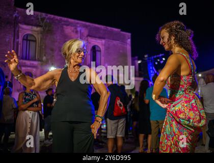 People enjoy Pizzica dance at a concert by Canzoniere Grecanico Salentino, or CGS, in Alessano, Lecce Province, Apulia, Italy. The band perform tradit Stock Photo