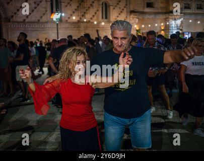 People enjoy Pizzica dance at a concert by Canzoniere Grecanico Salentino, or CGS, in Alessano, Lecce Province, Apulia, Italy. The band perform tradit Stock Photo