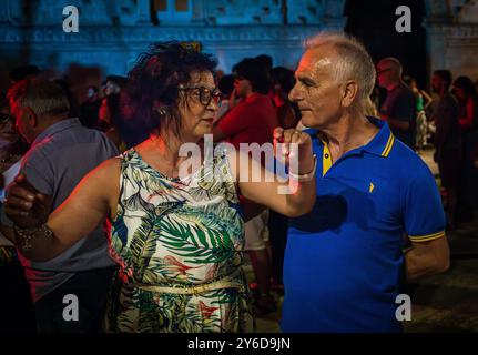 People enjoy Pizzica dance at a concert by Canzoniere Grecanico Salentino, or CGS, in Alessano, Lecce Province, Apulia, Italy. The band perform tradit Stock Photo