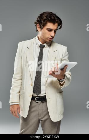 A young man dressed in fashionable formal wear interacts with a tablet, showcasing confidence and style. Stock Photo