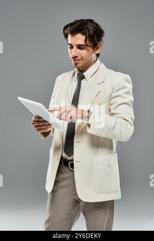 A young handsome man in formal attire confidently interacts with a tablet, showcasing modern elegance. Stock Photo