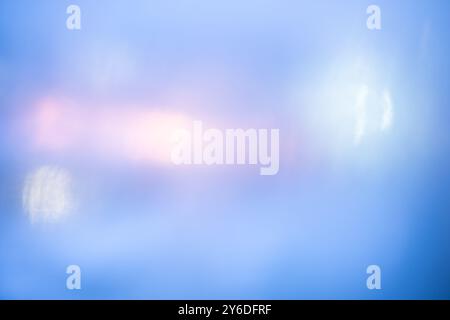 Defocused blue background with lights glowing through the misted window with drops. Stock Photo