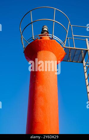 Image of a red lighthouse in the afternoon with a blue sky in the background Stock Photo