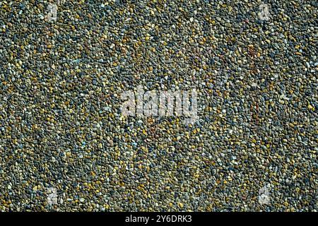 A diverse array of small, colorful stones tightly packed together showcases a rugged texture. The daylight highlights the various hues, creating a vib Stock Photo