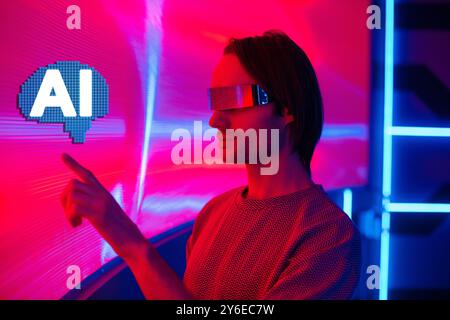 A futuristic man with smart neon glasses augmented reality touch air over a neon wall background Stock Photo
