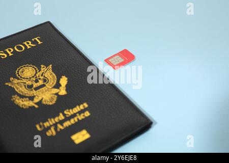 Modern SIM card and passport on light blue background, closeup Stock Photo