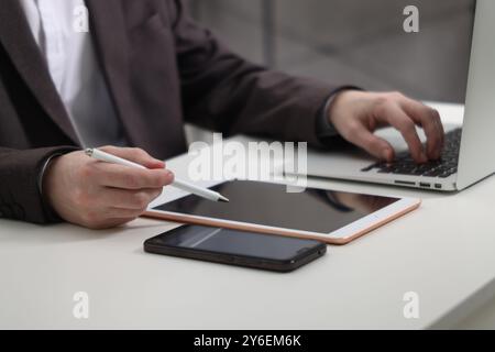 Businessman using different devices at white table indoors, closeup. Modern technology Stock Photo