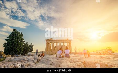 Tourists sitting on stones in front of Parthenon in the evening during sunset time, Athens, Greece. Picturesque sky at the Parthenon temple Stock Photo