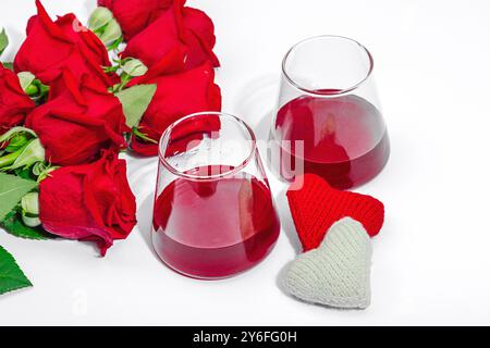 The concept of a romantic date. Two glasses of wine, handmade hearts, a bouquet of red roses. Trendy hard light, dark shadow, white background, flat l Stock Photo