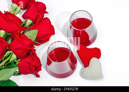 The concept of a romantic date. Two glasses of wine, handmade hearts, a bouquet of red roses. Trendy hard light, dark shadow, white background, flat l Stock Photo