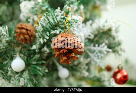 Closeup of a Dried Pine Cone Ornament Hanging on a Snow Covering Christmas Tree Stock Photo
