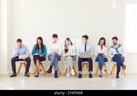 Happy different business people sitting on office chairs in row line, smiling diverse job seekers Stock Photo