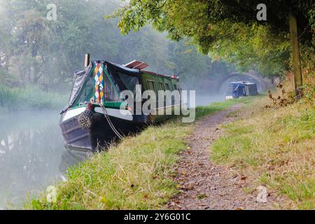 On a misty morning two narrowboats are moored by the towpath on the Grand Union Canal near Crick, Northamptonshire. Stock Photo