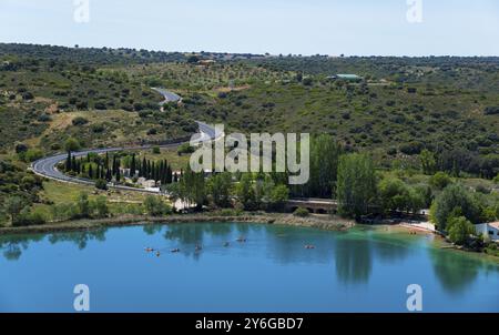 Panorama of a lake with surrounding trees, roads and hills under a clear sky, view from the viewing platform, Mirador de la Laguna del Rey, Lagunas de Stock Photo