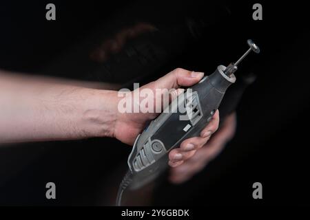 Close-up of man's hand holding a carpentry mototool with motion effect against black background Stock Photo