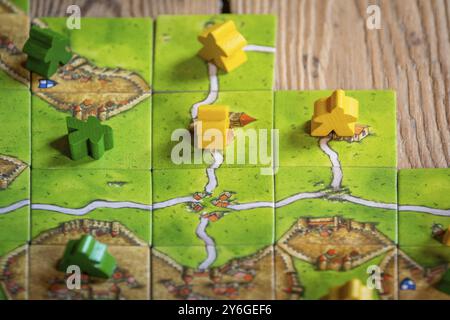 Antwerp, Belgium, November 2020: Illustrative Editorial: Carcassonne Board Game with tiles and meeples on wooden background, Europe Stock Photo